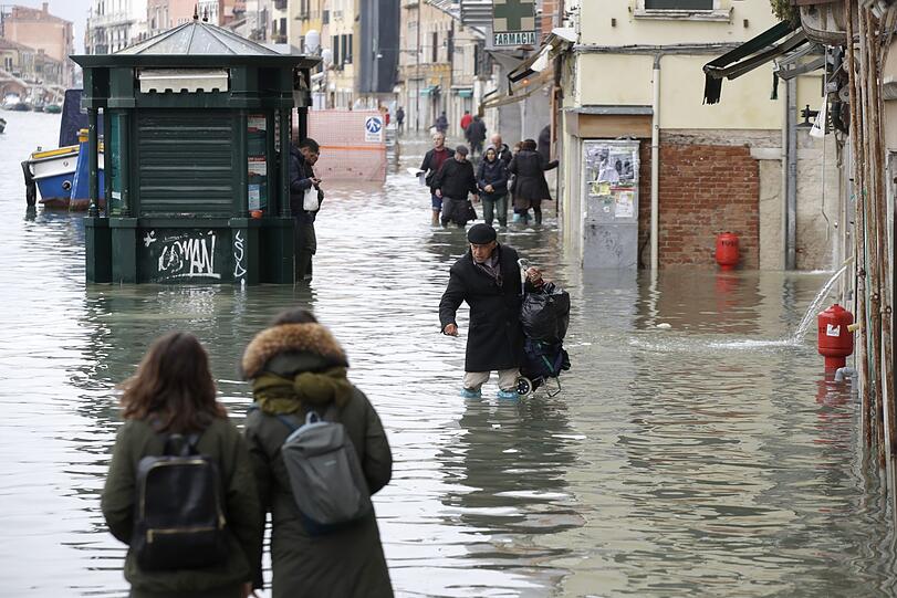 Passanten waten durch die Fluten. Fast das gesamte historische Zentrum steht unter Wasser.