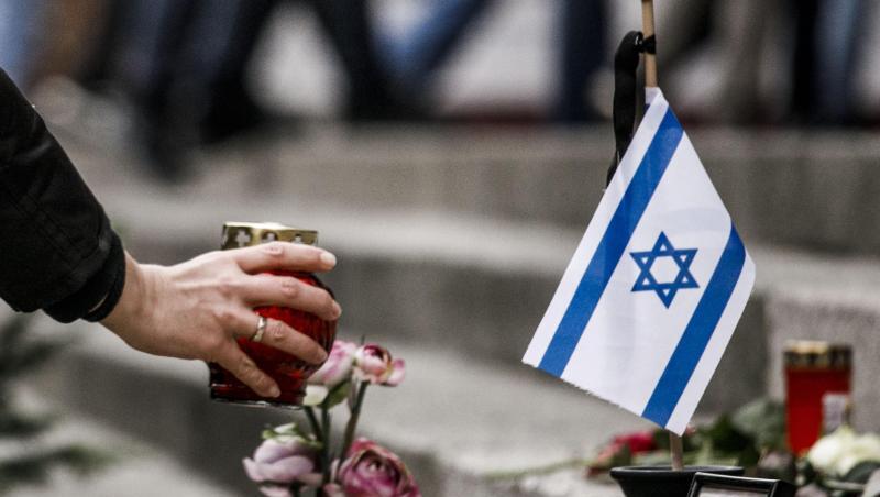 Eine Frau zündet am Breitscheidplatz am Mahnmal vor einer israelischen Fahne ein Kerzenlicht ab. Eine Frau zündet am Breitscheidplatz am Mahnmal vor einer israelischen Fahne ein Kerzenlicht ab.