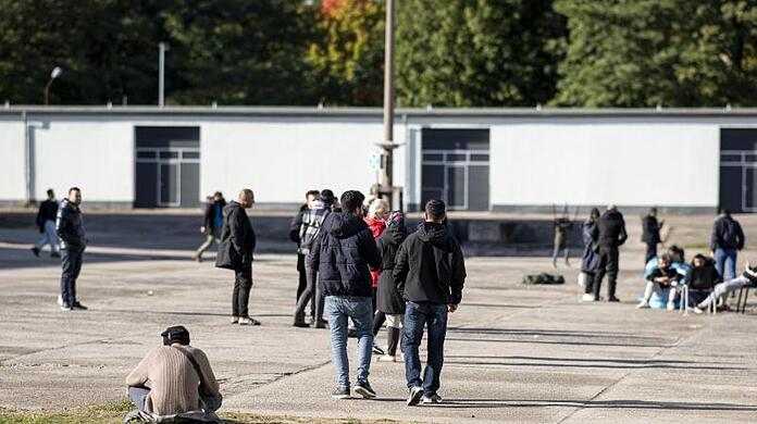Asylsuchende laufen in der Erstaufnahmeeinrichtung Eisenhüttenstadt über einen Platz. (Archivbild).