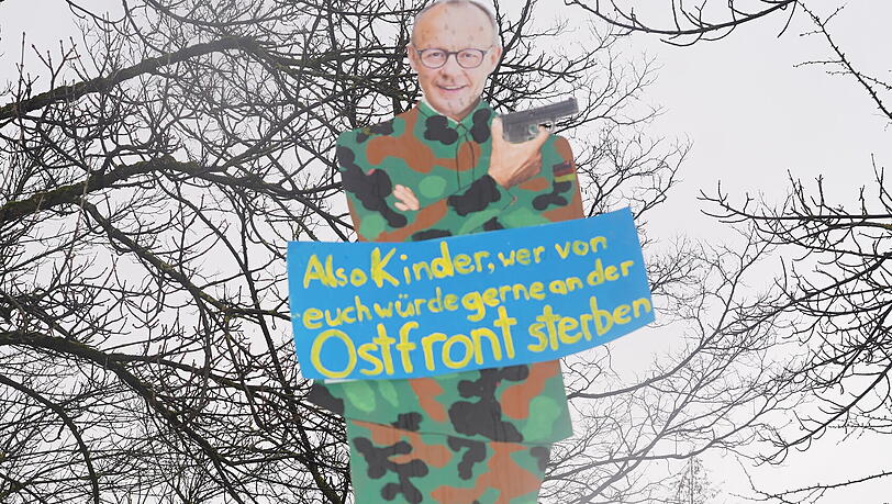 Merz als Karikatur: Provokantes Plakat bei der Demo.