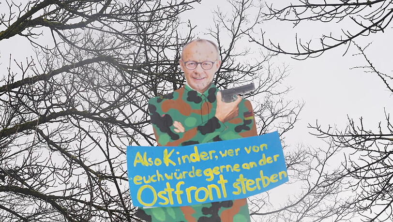 Merz als Karikatur: Provokantes Plakat bei der Demo. Merz als Karikatur: Provokantes Plakat bei der Demo.