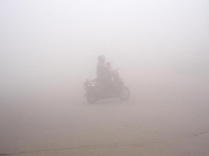 Smog in Delhi: Eine Frau bringt ihr Kind zur Schule.