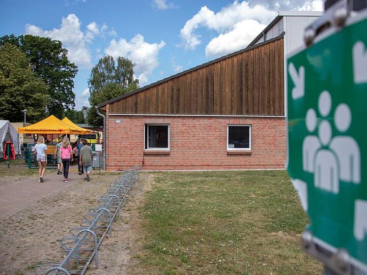 Kinder gehen in die Notunterkunft in einer Mehrzweckhalle.