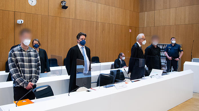 Die zwei wegen Mordes angeklagten Männer (l und 2.v.r.) stehen vor Beginn der Verhandlung mit ihren Anwälten Sarah Stolle und Alexander Betz (3.v.l.), Patrick Ottmann (4.v.r.) und Gerhard Bink (3.v.r.) im Sitzungssaal.
