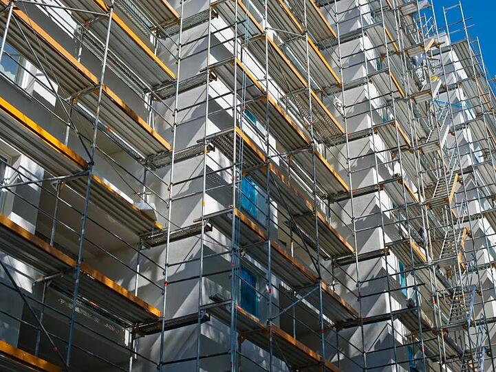 Ein Gerüst bedeckt die Fassade eines Wohnblocks. Foto: Ole Spata/Archivbild