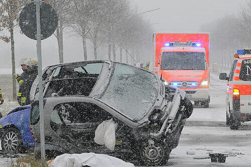Rettungsfahrzeuge stehen neben einem umgestürzten Pkw.