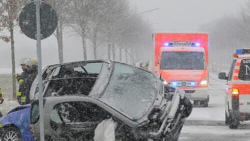 Rettungsfahrzeuge stehen neben einem umgestürzten Pkw. Rettungsfahrzeuge stehen neben einem umgestürzten Pkw.
