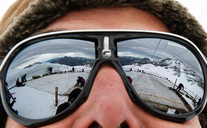Arbeiter decken auf dem Zugspitzplatt bei Grainau den Gletscher mit einer Plane ab, um ein Abschmelzen zu verhindern. Deutschlands einziger Gletscher soll waehrend der warmen Sommermonate mit der 500 bis 600 Quadratmeter grossen Plane vor Sonne und Regen geschuetzt werden.