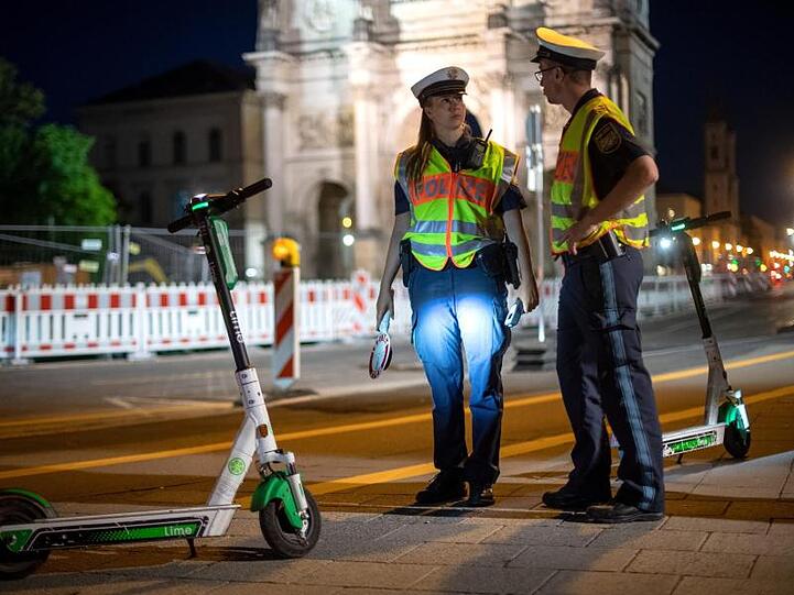 Polizisten stehen bei einer E-Tretroller-Kontrolle an der Straße.