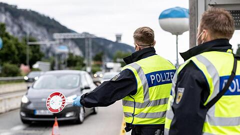 Deutsche Bundespolizisten beobachten an der Grenze zu Österreich auf der Autobahn A93 den Verkehr.