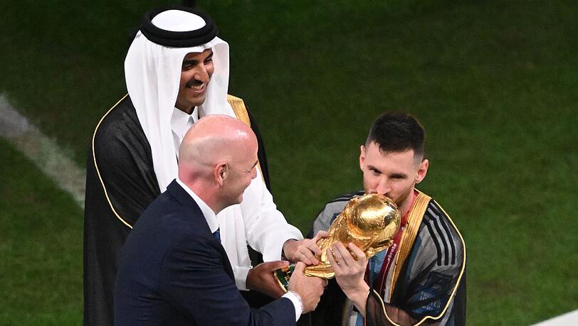 Der Emir von Katar und FIFA-Präsident Gianni Infantino übergeben Lionel Messi den WM-Pokal.
