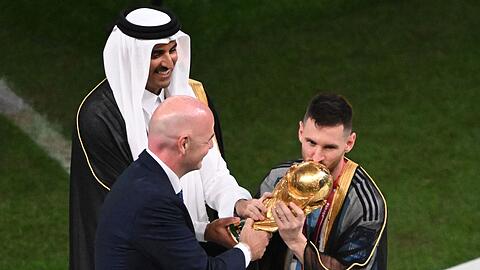 Der Emir von Katar und FIFA-Präsident Gianni Infantino übergeben Lionel Messi den WM-Pokal.