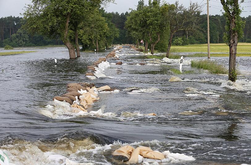 Ein Hilfsdamm aus Sandsäcken ist am 14.06.2013 auf einer Landstraße zwischen Wulkau (Sachsen-Anhalt) und dem Nachbarort Kamern vom Hochwasser überspült.