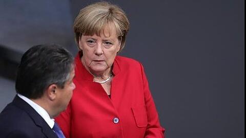 Kanzlerin Angela Merkel unterhält sich im Bundestag mit dem Bundeswirtschaftsminister und SPD-Vorsitzenden Sigmar Gabriel. Foto: Michael Kappeler/dpa