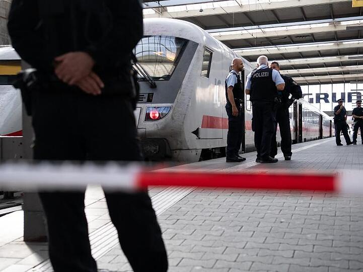 Polizisten stehen hinter einer Absperrung neben einem Zug an einem Gleis im Münchner Hauptbahnhof. Foto: Sven Hoppe