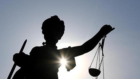 Statue der Justitia mit einer Waage und einem Schwert in den Händen.