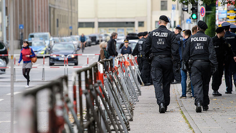 Polizisten gehen vor dem Oberlandesgericht an einem Absperrzaun entlang.