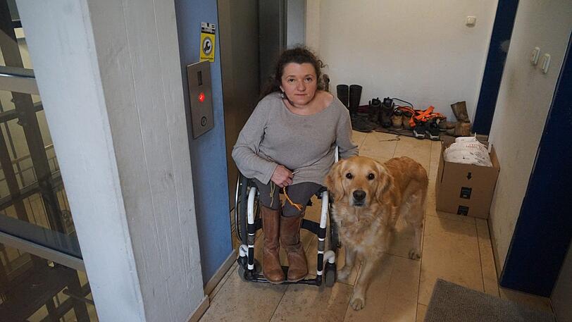 Heidrun Graf mit ihrem Hund Franzi neben dem defekten Fahrstuhl.