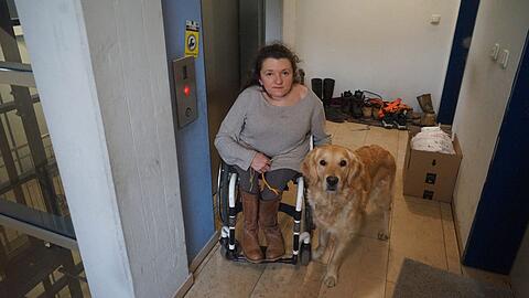 Heidrun Graf mit ihrem Hund Franzi neben dem defekten Fahrstuhl.