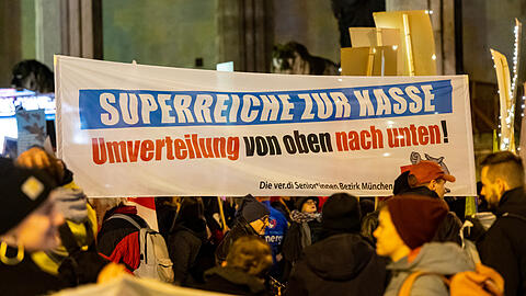 Demonstranten halten während einer Protestkundgebung des Bündnisses "Superreiche zur Kasse" auf dem Odeonsplatz ein Plakat mit der Aufschrift "Superreiche zur Kasse Umverteilung von oben nach unten!". Der Deutsche Gewerkschaftsbund (DBG) und verschiedene andere Verbände und Parteien haben am Donnerstagabend in München für soziale Gerechtigkeit und mehr Unterstützung in der Energiekrise demonstriert.