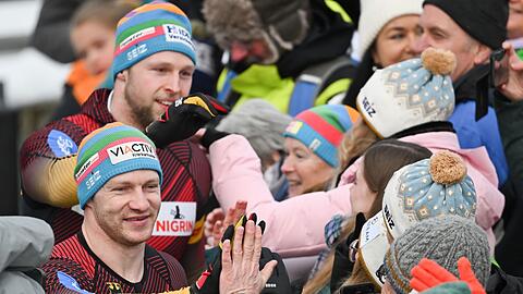 Francesco Friedrich (vorne l) und Alexander Schüller (hinten l) klatschen nach ihrem Sieg mit Fans ab.