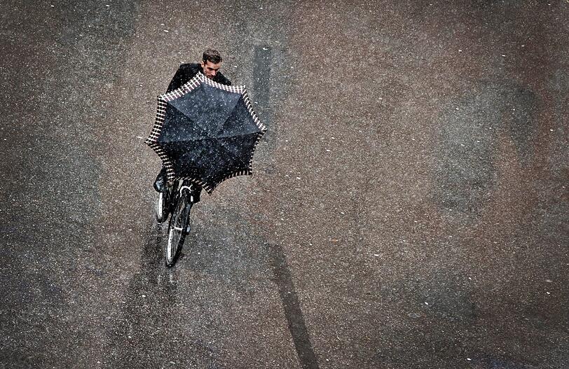 In der Münchner Innenstadt bleibt es erstmal beim Schneeregen. Für Radler eine besondere Herausforderung, auch und gerade mit Schirm.