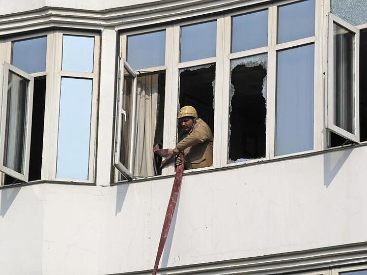 Ein Feuerwehrmann rollt nach dem Einsatz im Hotel einen Schlauch ein. Auch andere Gebäude in der Gegend sollen nun auf Brandsicherheit überprüft werden.