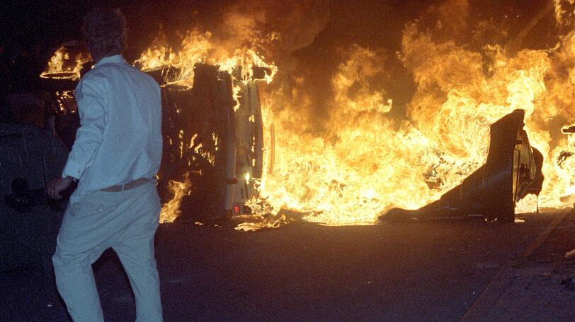 Rostock Lichtenhagen vor 25 Jahren: Am Rande des Geschehens geht ein Pkw in Flammen auf.