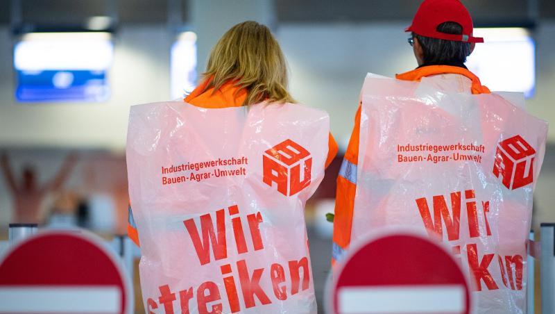 Zwei Mitarbeiterinnen von Reinigungsfirmen stehen mit Streikwesten am Flughafen Münster Osnabrück. Foto: Guido Kirchner/dpa Zwei Mitarbeiterinnen von Reinigungsfirmen stehen mit Streikwesten am Flughafen Münster Osnabrück. Foto: Guido Kirchner/dpa