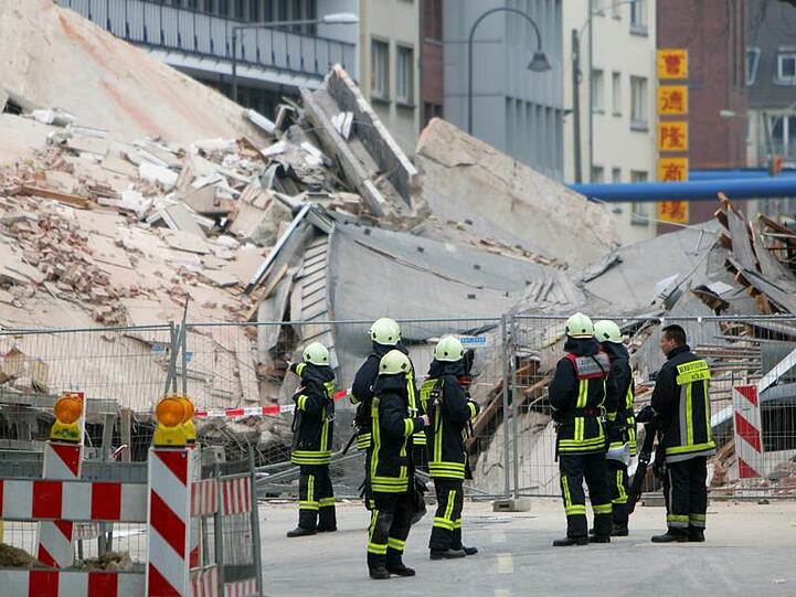 Der Trümmerhaufen: Rettungskräfte stehen vor den Überresten der zerstörten Gebäude.