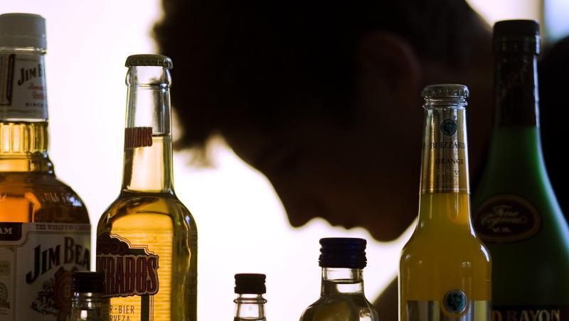 Ein Mann sitzt hinter Flaschen mit Alkohol. Foto: Jens Büttner/Archivbild Ein Mann sitzt hinter Flaschen mit Alkohol. Foto: Jens Büttner/Archivbild