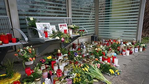 Kerzen und Blumen stehen und liegen im Bahnhof Brokstedt in einem Wartehäuschen.