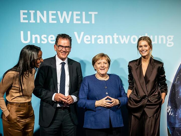Bundeskanzlerin Angela Merkel und Entwicklungsminister Gerd Müller stehen zusammen mit den Ministeriums-Botschafterinnen Sara Nuru (l) und Toni Garrn (r) bei der Veranstaltung "Eine Welt - Unsere Verantwortung".