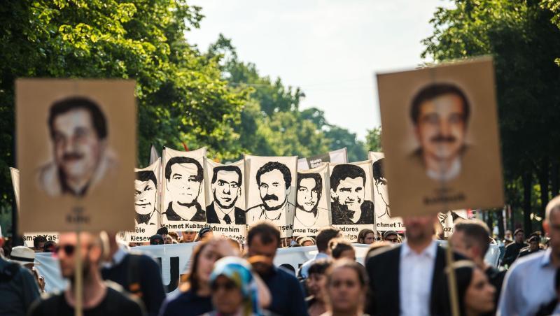Demonstranten halten bei einer Kundgebung Schilder mit Porträt-Abbildungen der NSU-Opfer.