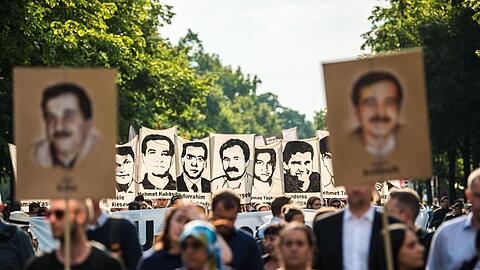 Demonstranten halten bei einer Kundgebung Schilder mit Porträt-Abbildungen der NSU-Opfer.