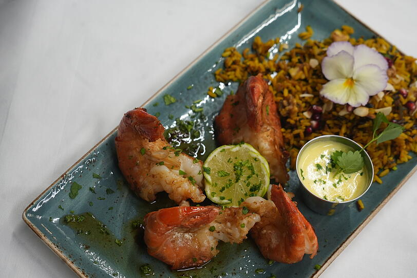 Scampi Antillaise vom Grill, flambiert mit Rum, Tamarinden-Reis und Safran-Wei&szlig;wein-So&szlig;e.