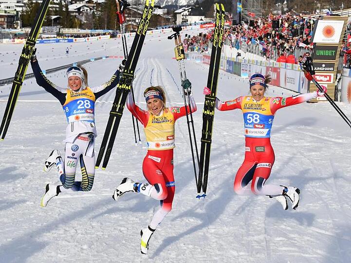 Therese Johaug (M) und Ingvild Flugstad Östberg (r) und Frida Karlsson feiern in Seefeld ihre Langlauf-Medaillen.