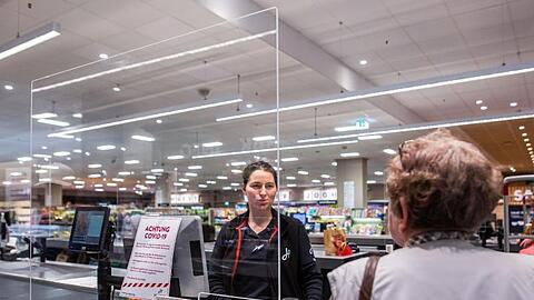 In einem Supermarkt in Rheinfelden in Baden-Württemberg wird die Kassiererin von einer Plexiglasscheibe geschützt.