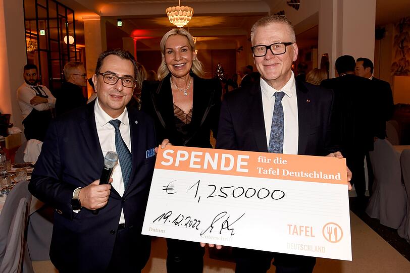 Stavros Kostantinidis und Ehefrau Saskia Greipl übergeben Tafel-Präsident Jochen Brühl den Scheck