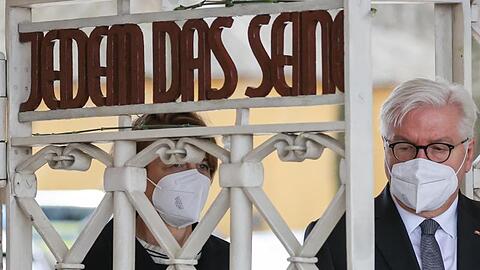 Bundespräsident Frank-Walter Steinmeier und seine Frau Elke Büdenbender gehen durch das Lagertor von Buchenwald, das den zynischen Schriftzug "Jedem das Seine" der Nationalsozialisten trägt.