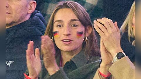 Lena Wurzenberger mit Deutschlandfahne im Gesicht und dem pinken Trikot unter ihrer Jacke beim Spiel gegen die Niederlande.