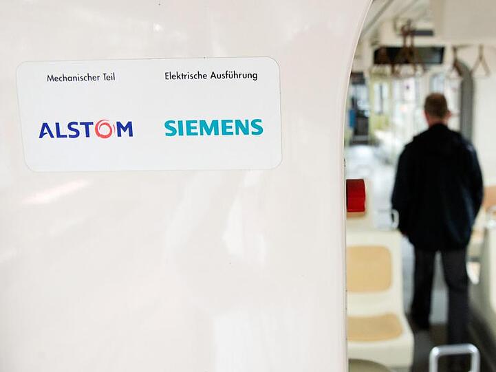 Die Logos von Alstom und Siemens kleben in einem Zug. Foto: Julian Stratenschulte/Archiv