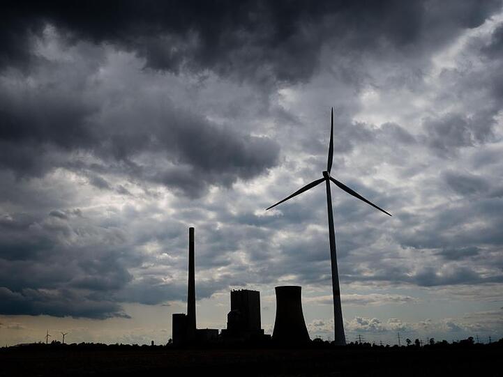 Dunkle Wolken ziehen über ein Kohlekraftwerk und Windrädern hinweg. Foto: Julian Stratenschulte/Archivbild