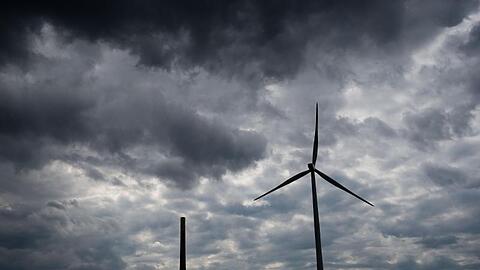 Dunkle Wolken ziehen über ein Kohlekraftwerk und Windrädern hinweg. Foto: Julian Stratenschulte/Archivbild