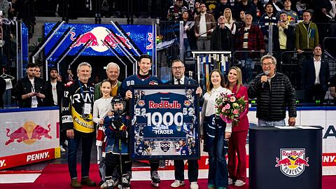 Hut ab, Kapitän! Im Beisein seiner Familie erhält Patrick Hager (4. v. l.) von EHC-Boss Christian Winkler ein Trikot mit der Nummer 1000. Großen Applaus von den Rängen erntet auch Stefan Schneider (r.), der seinen Stadionsprecher-Ruhestand extra für Hager unterbricht.