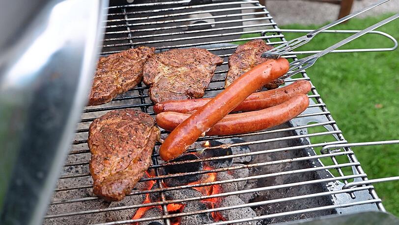 Ein bekannter Anblick: Fleisch und Würstl liegen im Sommer auf einem Holzkohlegrill.