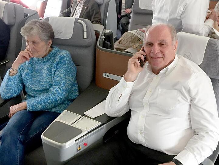 Uli Hoeneß (r), Ehrenpräsident des FC Bayern, telefoniert neben seiner Frau im Flugzeug nach London. Foto: Klaus Bergmann/dpa