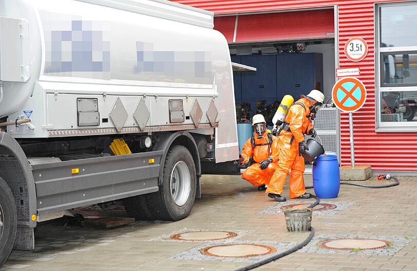 Säureunfall: Einsatzkräfte der Münchner Feuerwehr nehmen unter schwerem Atemschutz die ausgetretenen Stoffe in Spezialfässer auf und stellen den Brandschutz sicher.