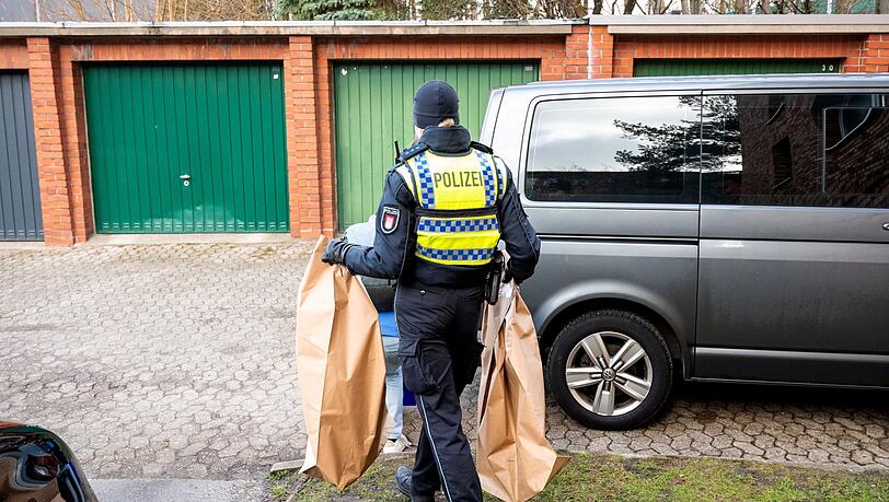 Eine Polizistin trägt Beweismittel aus einem Mehrfamilienhaus. Eine Hundertjährige soll dort von ihrem Enkel getötet worden sein.