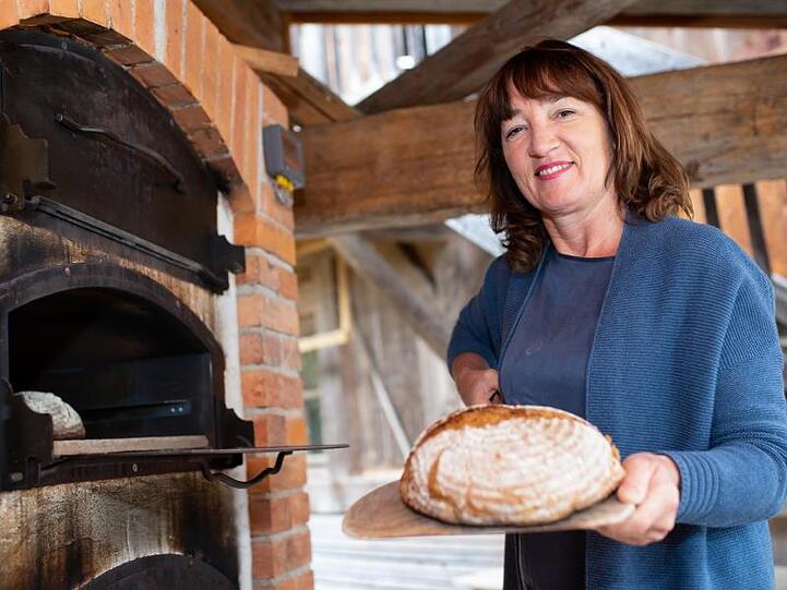 Müllerin Annelie Wagenstaller holt in der Wagenstaller Mühle ein Brot aus einem Ofen. Foto: Sven Hoppe/dpa